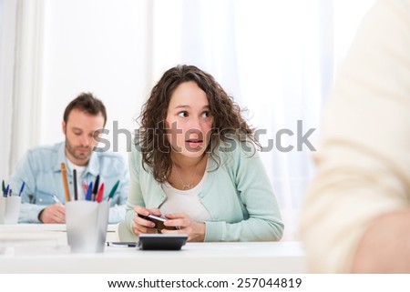 View of a Young attractive woman cheating with mobile during exam