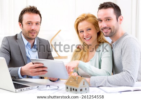 View of a Real estate agent present project on tablet to a young couple