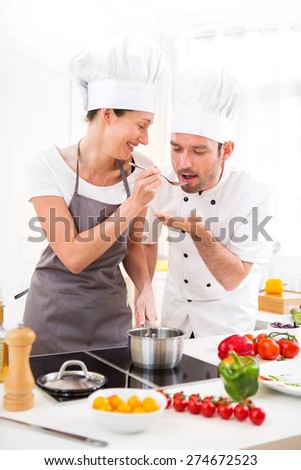 View of a Young chef training a young attractive girl to cook