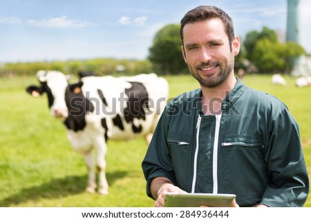 View of a young attractive farmer in a pasture with cows