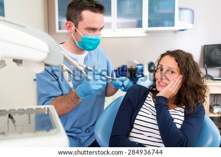 View of a Young attractive woman scared to being cured by a dentist