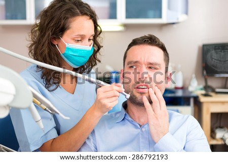 View of a Young attractive man scared to being cured by a dentist