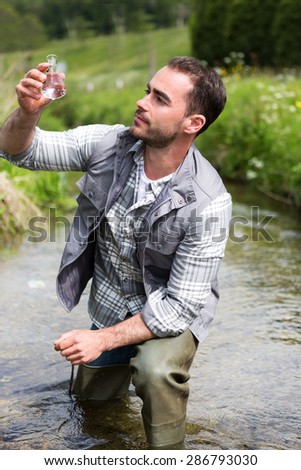 View of a Biologist take a sample in a river in order to do some test
