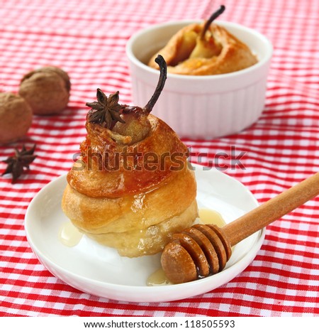 Dessert from a pear with honey in a puff test on a background a nuts and checked table-cloth
