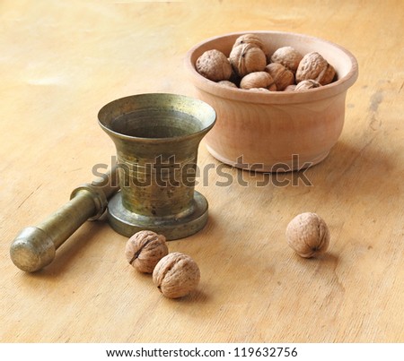 Bronze mortar with pestle and bowl of walnuts  on a white background