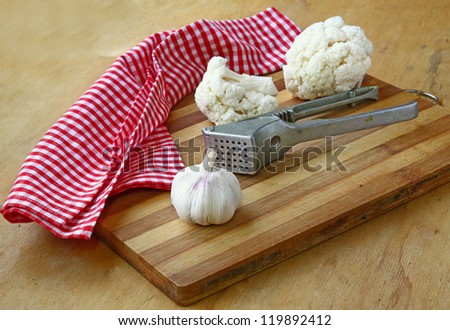 Cauliflower and garlic on a wooden chopping board on a kitchen