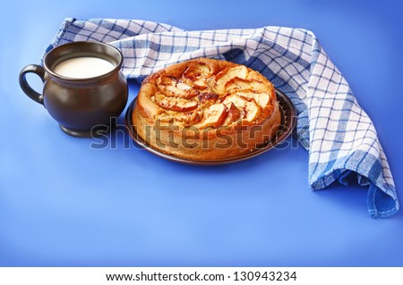 Handmade apples cake and ceram cup with milk on a dark blue background