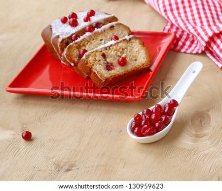 Cranberry cake on a red dish  and porcelain spoon with the berries of cranberry on a wooden table