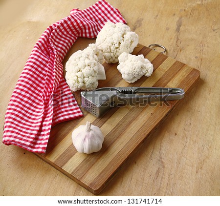 Cauliflower and garlic on a wooden chopping board on a kitchen