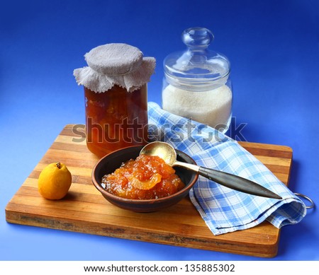 Jar of homemade jam from a quince and jar with sugar on a wooden table