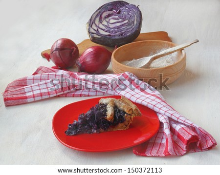 Portion of vegan pie on the background of the ingredients: red cabbage and onions