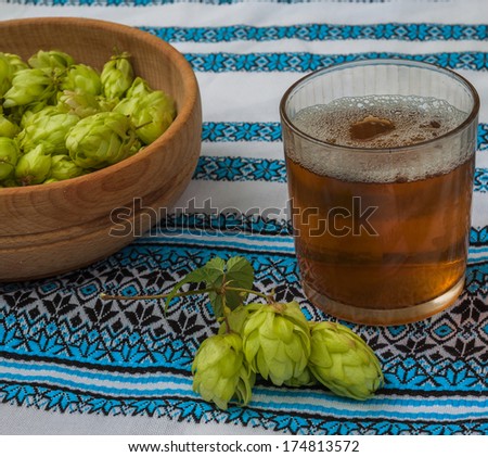 Glass withGlass with a drink of hops on the background of traditional Ukrainian embroidered towel and  branch of hops