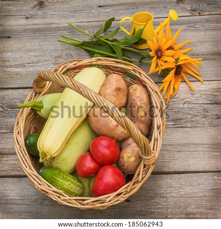 Basket with vegetables and a bouquet of yellow rudbeckia on a old table
