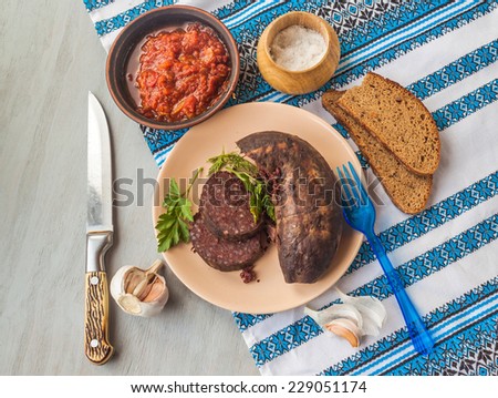 Ring pudding sausages on a plate with a slice of garlic and a piece of bread