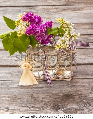 Lilac Bouquet and straw angel figurine on an old wooden table (mass-produced)