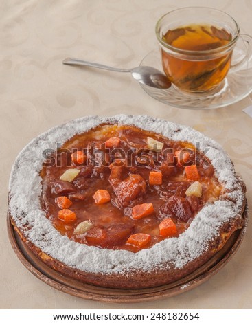 Pumpkin pie decorated with candied fruit and cream and a cup of green tea