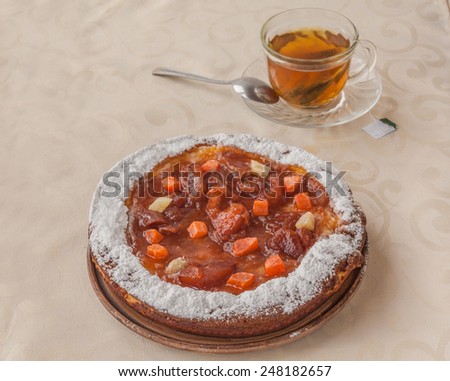 Pumpkin pie decorated with candied fruit and cream and a cup of green tea