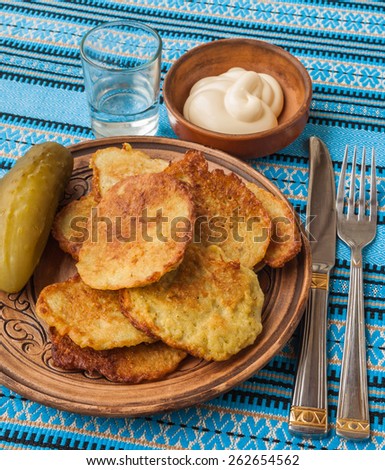 Traditional Ukrainian homemade potato pancakes potato with sour cream and  glass of vodka and salted cucumber