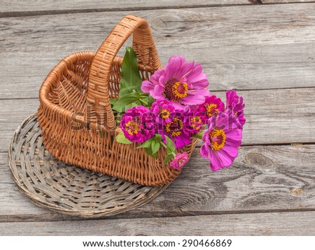Bouquet with zinnia in a basket on an old wooden table