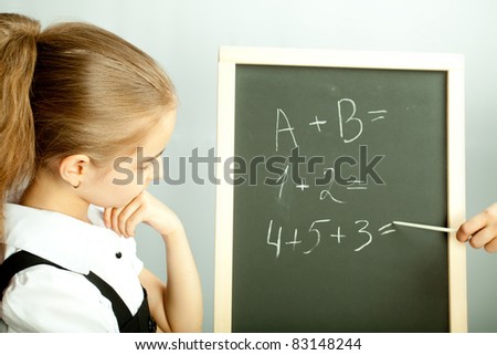 School girl looking at the blackboard with exercises and thinking about answers