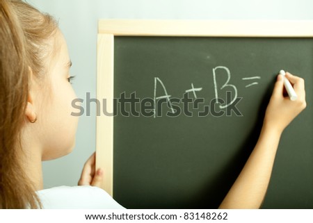 School girl write exercise on the black board in the class
