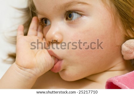 stock photo Beautiful baby girl sucking her thumb and hugging her doll in