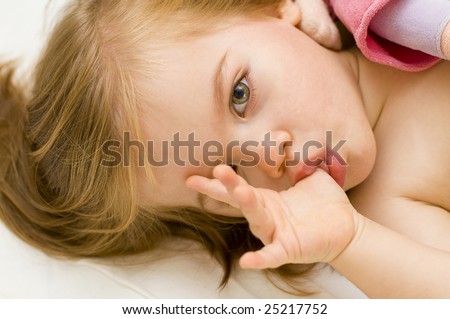 stock photo Beautiful baby girl sucking her thumb and hugging her doll in 