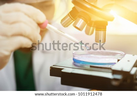 Pipette dropping a sample into a test pad,  Medical doctor or scientist with microscope, equipment and science experiments , glassware containing chemical liquid, researching samples in laboratory