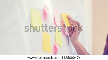 Business people meeting at office and use post it notes to share idea. Brainstorming concept. Sticky note on glass wall.business women working and communicating together in creative office