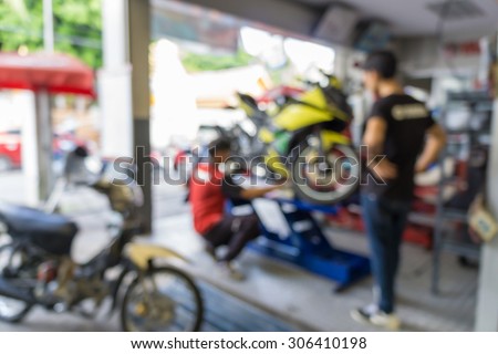 Blurred of motorcycle technician repairing the motorcycle in garage background.
