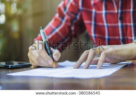 writing,Businessperson Signing Contract,Man writing paper at the desk, man writing with pen and reading books at table,man Signing, Contract, Form.\
in office ,morning light ,selective focus.copy space