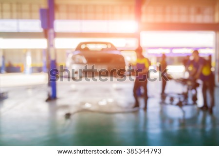 Blurred background of car technician repairing the car in garage,mechanics fixing car in a workshop background,car suspension detail of lifted automobile at repair service station,vintage color.
