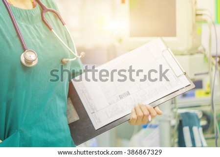 female doctor with stethoscope on hospital corridor holding clipboard  with an operating room at the background ,Healthcare and medical concept,selective focus.