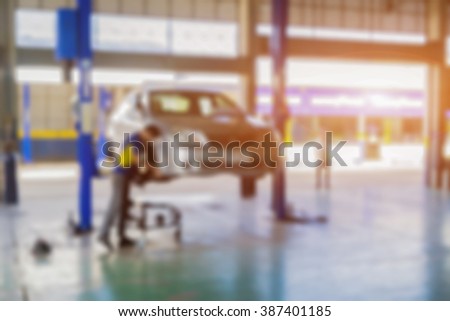 Blurred background of car technician repairing the car in garage,mechanics fixing car in a workshop background,car suspension detail of lifted automobile at repair service station,vintage color.