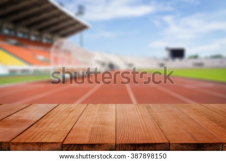 Wood table top on blurred background of Red running tracks in sport stadium  - can be used for display or montage your products