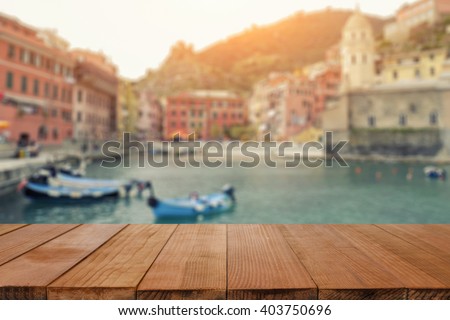 Wood table top on Blurred background of Manarola village on cliff rocks and sea at sunset.Seascape in Five lands, Cinque Terre ,Italy Europe.vintage tone color,can be used display your products