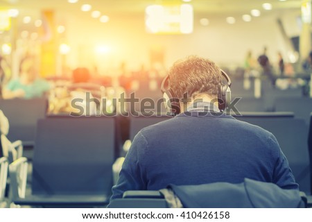 Back view of Business man while listening to music.young man in headphones working on laptop while sitting at airport,Businessman Relaxing Listening To Music,selective focus ,vintage color
