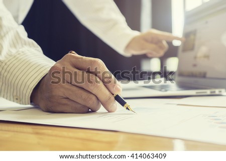 Close-up Of Businessperson Signing Contract,Man writing paper at the desk, man writing with pen and reading books at table,man Signing, Contract, Form. in office ,morning light ,selective focus.