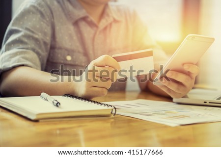 Woman verifies account balance on smartphone with mobile banking application.Online payment,Women\'s hands holding a credit card and using smart phone for online shopping,selective focus,vintage color