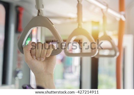 Handle on ceiling of bus,handle on a train,The handle on the MRT, prevent toppling.underground railway system or metro,people holding onto a handle on a train and the bus,selective focus,vintage color