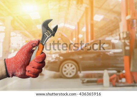 Car repair.Hand of car technician auto mechanic with a wrench.Auto mechanic working in garage. Repair service.car technician repairing the car in garage background in car repair station.vintage tone