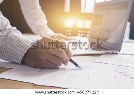 Businessperson Signing Contract, the man writing with pen and reading books at table,Businessman signing of modest agreements Form In office,male hands holding pen, morning light, selective focus.