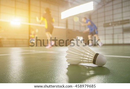 A set of badminton concept.Badminton ball (shuttlecock) and racket on court floor,Paddle ,the shuttlecock and badminton courts with players competing in modern gym,selective focus,vintage color
