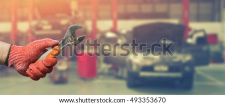 Car repairing,Hand of car technician auto mechanic with a wrench working in garage. Repair service in car repair station.vintage tone,for banner