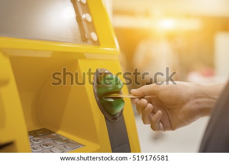Hand inserting ATM card into bank machine to withdraw money,People stand in a queue to use the ATMs of a bank. Person receiving money from the ATM.vintage color