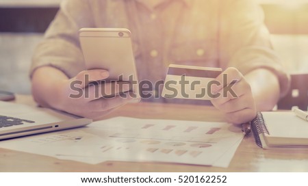 Woman verifies account balance on smartphone with mobile banking application.Online payment,Women\'s hands holding a credit card and using smart phone for online shopping,selective focus,vintage color