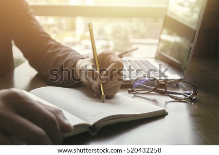 Young male student writes information from portable net-book while prepare for lectures in University campus,hipster man working on laptop computer while sitting in cafe,vintage color,selective focus