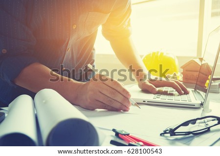 architect man working with laptop and blueprints,engineer inspection in workplace for architectural plan,sketching a construction project ,selective focus,Business concept vintage color
