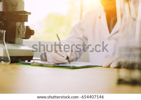 Medical research. Professional chemist young  man writing on his clipboard while working at the laboratory ethnicity profession occupation people medicine clinical biology ,Medical science concept