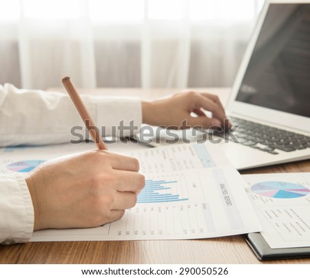 Businessmen are analyzed data from report and a laptop computer.